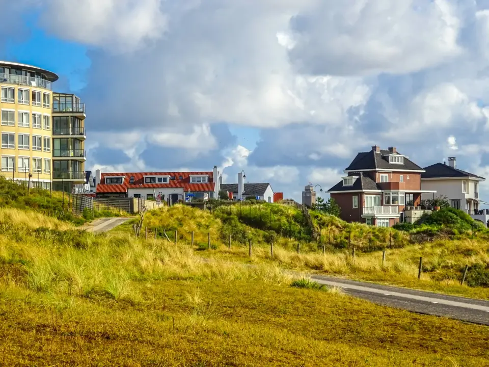 Huizen en een appartementengebouw net achter de duinen met helmgras